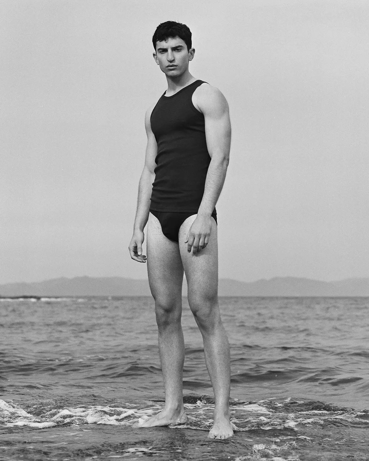 Man on a roc wearing the organic cotton black brief Etor, made in Portugal | Hemen Biarritz