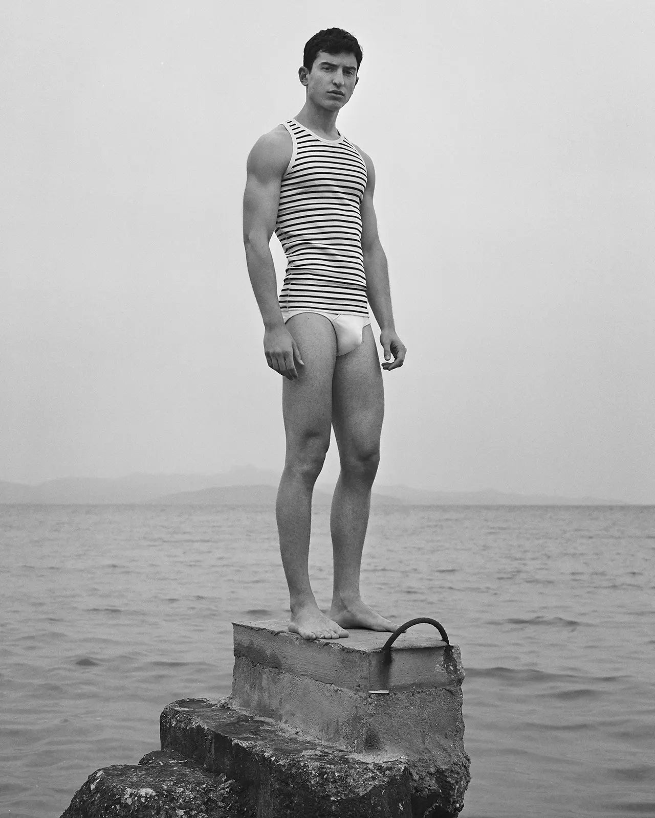 Man on a roc wearing the organic cotton breton stripe tank top Gari, made in Portugal | Hemen Biarritz