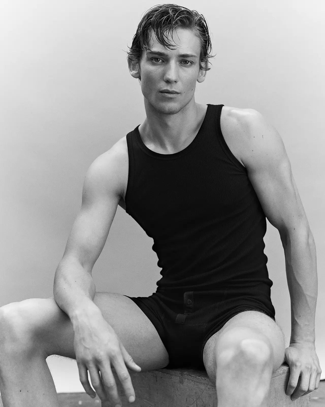 Man seated wearing the organic cotton black tank top Gari, made in Portugal | Hemen Biarritz